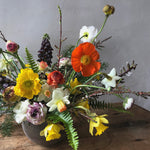 Fresh garden style blooms bursting with color overflow from the vase.